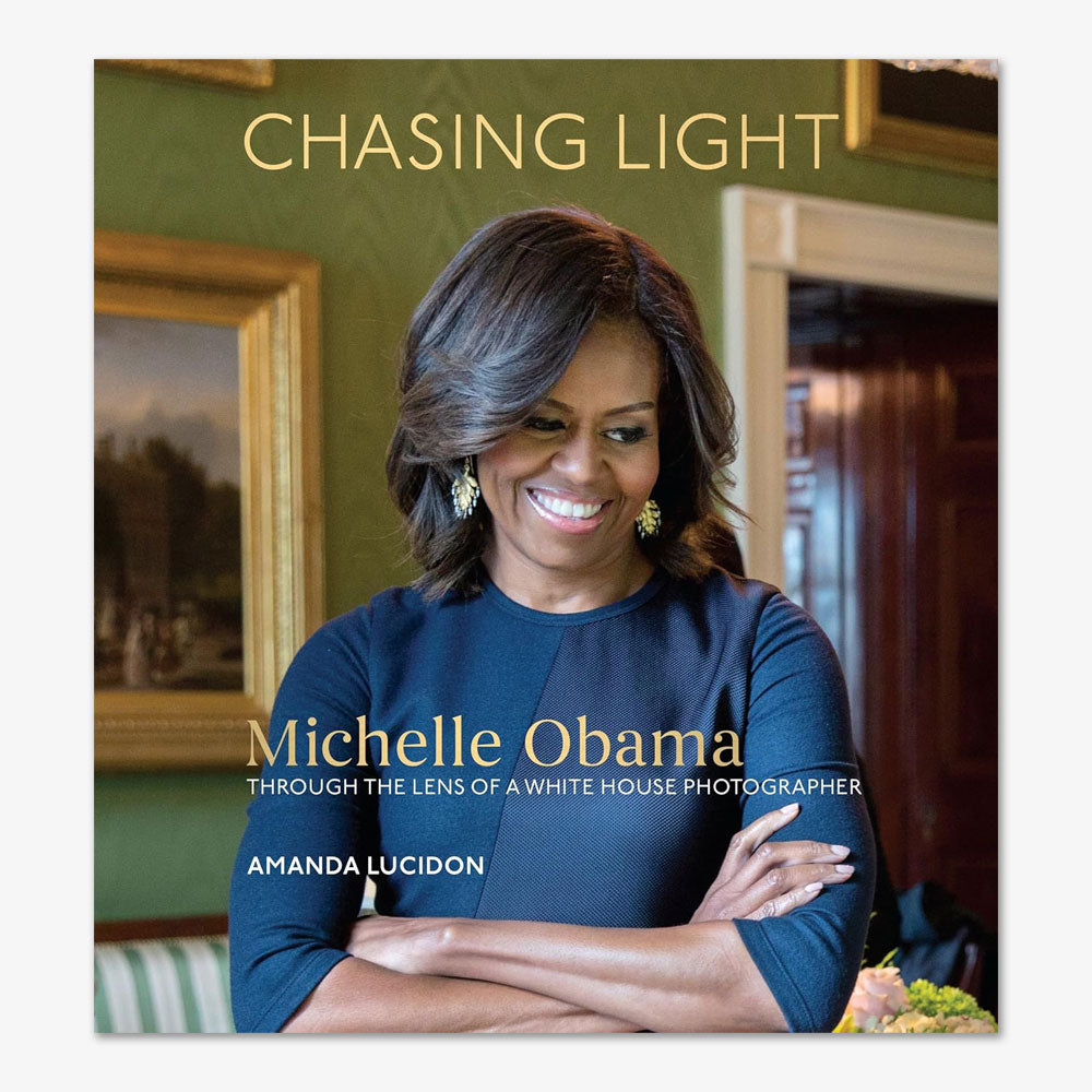 The cover of *Chasing Light: Michelle Obama Through the Lens of a White House Photographer* features Michelle Obama smiling with arms crossed, as captured by Amanda Lucidon, offering an intimate look into her White House years.