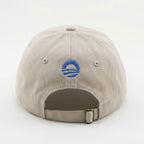 The Obama Presidential Center Hope Cap – Stone is a beige cap with a blue embroidered "O" logo and three horizontal lines, an adjustable strap with metal clasp, offering a stylish tribute to the Obama Foundation.