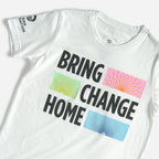 The Obama Foundation Youth T-Shirt features "BRING CHANGE HOME" in bold black text with green-yellow circles, orange rays, and blue dots beside each word. Inspired by the Obama Foundation, with the AMA FOUNDATION logo on the sleeve.