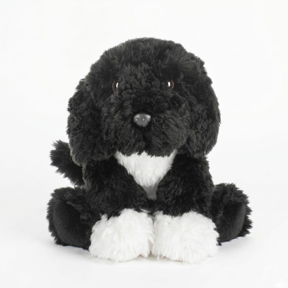 The Bo Plush, a soft black and white stuffed dog inspired by the Obama family's pet Bo, sits upright with floppy ears against a plain white background—a unique presidential keepsake.