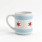 Show your Chicago pride with the Chicago Star Mug, a white porcelain mug decorated with blue stripes and red six-pointed stars inspired by the city flag—perfect for Windy City enthusiasts and Obama Foundation fans.