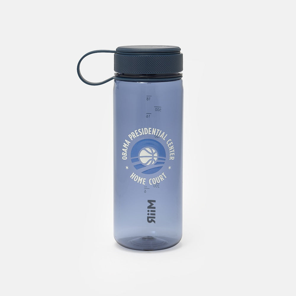 The Obama Presidential Center Hope Water Bottle is translucent blue with a dark lid and carrying loop, features measurement markings, a Home Court logo, basketball graphic on the front, and celebrates Chicago’s South Side.