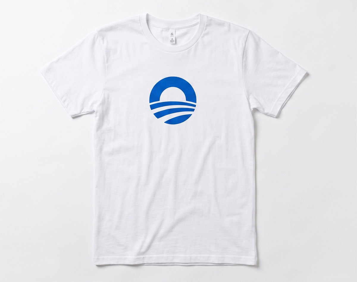 The Obama Presidential Center Symbol T-Shirt in white features a blue circular logo with a sun over three wave-like lines, centered on the chest. Inspired by the Center, this design reflects the spirit of Bring Change Home.