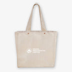The Obama Presidential Center "You Are America" Speech Tote is a beige canvas bag with two handles, featuring the center’s logo and text in white on the front.