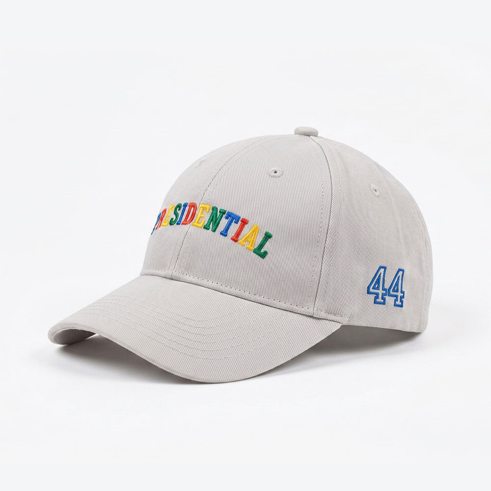 The Presidential Embroidered Youth Cap is a light gray kids' hat featuring "PRESIDENTIAL" in multicolored embroidery on the front and the number 44 in blue on the side—a standout Obama Foundation merchandise piece.