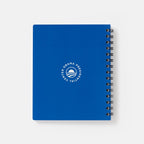 The Obama Presidential Center Bring Change Home Notebook is a blue spiral-bound notebook with "Bring Change Home" and the Obama Foundation logo in white on the front cover, shown against a plain white background.