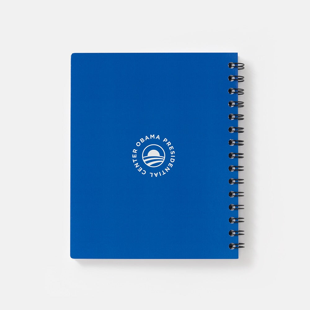 The Obama Presidential Center Bring Change Home Notebook is a blue spiral-bound notebook with "Bring Change Home" and the Obama Foundation logo in white on the front cover, shown against a plain white background.