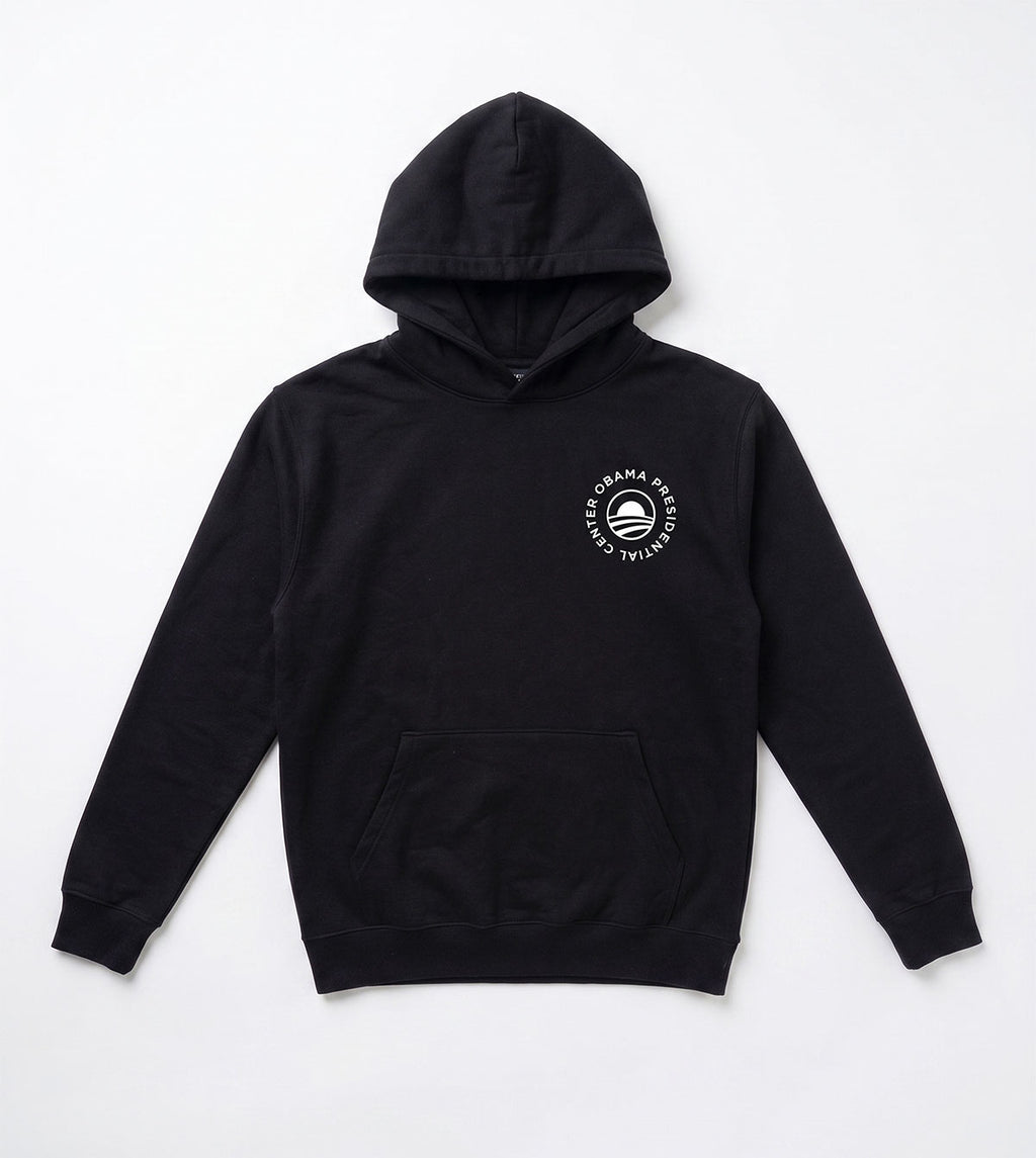 The Obama Presidential Center Script Hooded Sweatshirt is a black hoodie with a front pocket and a white circular logo on the left chest, featuring “Obama Presidential Center” around a stylized O icon, laid flat on a white background.