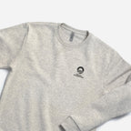 The Obama Foundation Sweatshirt is an oatmeal heather crewneck with the foundation's logo and text in black on the left chest, shown against a white background.