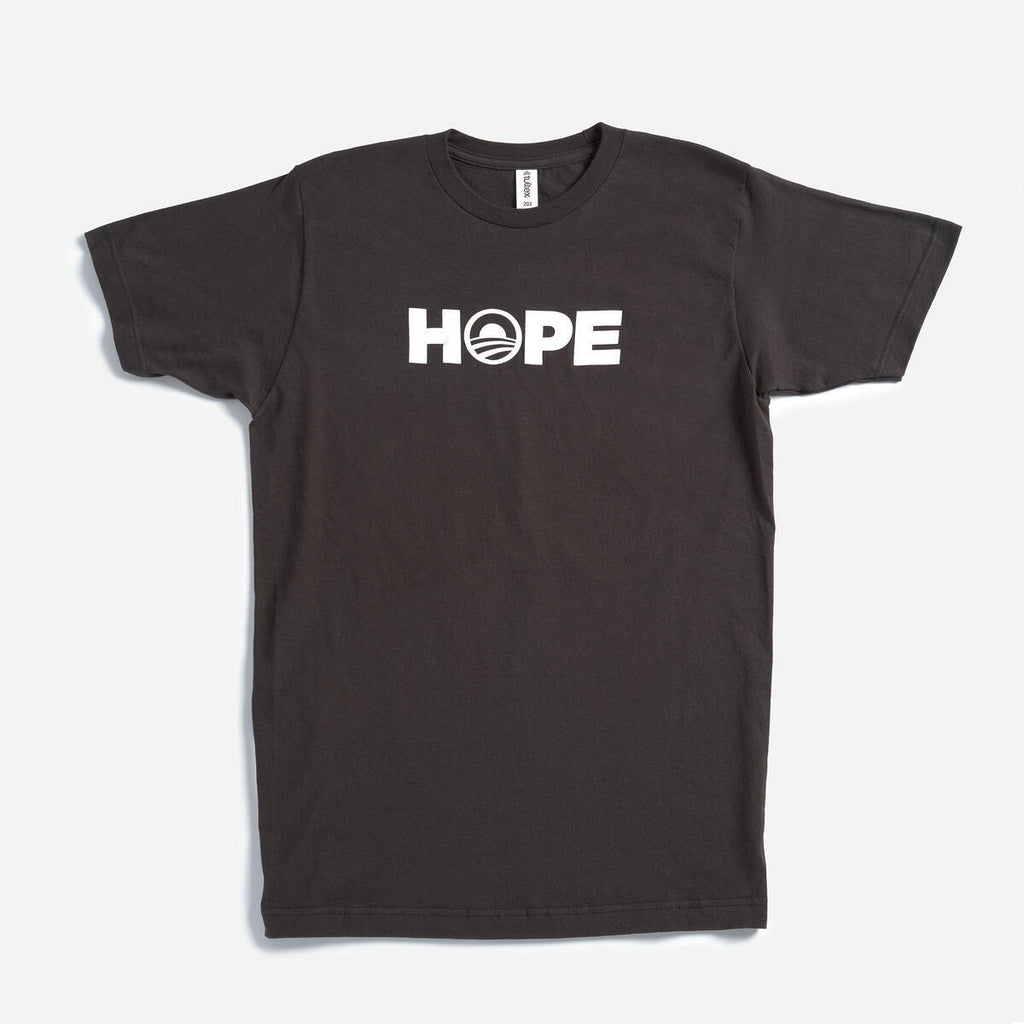 The Obama Foundation "Hope" T-shirt features “HOPE” in white across the chest on a black shirt, with the O creatively designed as a rising sun, inspired by the original Obama Foundation tee.