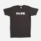 The Obama Foundation "Hope" T-shirt features “HOPE” in white across the chest on a black shirt, with the O creatively designed as a rising sun, inspired by the original Obama Foundation tee.
